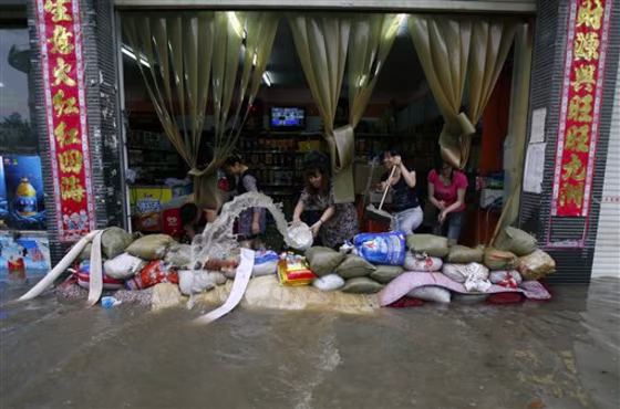 A woman uses a pail to remove water from a flooded store in Wuhan, China, on Saturday.